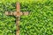 Wooden crucifix with INRI written on it in front of a hedge with green leaves