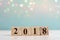 Wooden cube with 2018 label for new year decoration on bokeh background