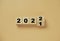 Wooden cube block flipping from 2021 to 2022 on orange background , preparation for merry Christmas and happy new year