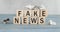 Wooden cube with flip block FAKE to FACT News word on table background. News, solution