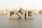 wooden cube with the letter from the PTE word. wooden cubes standing on gray background. PTE - short for Pearson Tests