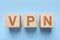 Wooden cubes with acronym VPN on light blue background, flat lay