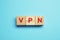 Wooden cubes with acronym VPN on light blue background, top view