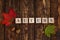 Wooden cubes with Autumn inscription on a wooden dark background with colorful maple leaves and acorn