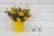 Wooden cubes calendar July 3 and yellow cup with bright colored flowers against white brick wall. Template calendar date