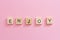 Wooden cubes inscription Enjoy on pink background