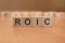 wooden cubes with the inscription - ROIC, brown background