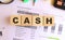 Wooden cubes with letters on the table in the office. Text CASH. Financial concept