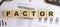 Wooden cubes with letters on the table in the office. Text FACTOR. Financial concept