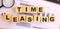 Wooden cubes with letters on the table in the office. Text TIME LEASING