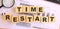 Wooden cubes with letters on the table in the office. Text TIME RESTART