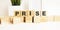 Wooden cubes with letters on a white table. The word is PRISE. White background