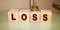 Wooden cubes with LOSS word on wooden table. Financial loss business concept. Memory loss dementia mental health concept