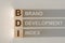 Wooden cubes with the word BDI - brand development index, with a falling shadow on a gray background