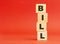 Wooden cubes with word BILL. Wooden cubes on a red background. Free space on the left