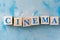 Wooden cubes with word CINEMA on blue table.