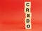 Wooden cubes with word CREDO. Wooden cubes on a red background. Free space on the left