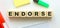 Wooden cubes with word ENDORSE on the office desk. Folder and other office supplies.