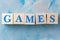 Wooden cubes with word GAMES on blue table.