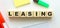 Wooden cubes with word LEASING on the office desk. Folder and other office supplies