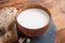 Wooden cup of milk and bread slices on kitchen round slate board