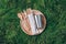 Wooden cutlery, bamboo plate, metal cup, straw on green grass, moss background. Top view. Copy space. Zero waste