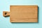 Wooden cutting board on blue background, from above