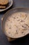 Wooden cutting board with a bowl filled with a creamy mushroom soup and a slice of bread beside it