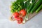 Wooden cutting board with fresh vegetables on stone concrete table. Top view tomatoes, cucumbers, onion, parsley. Fresh healthy