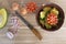 Wooden cutting board with knife, fresh onions, tomato and avocado