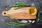 Wooden cutting board, olive oil, rosemary plant, salt, garlic and pepper on black table from above for food cooking background or