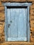 Wooden cyan window shutter in a traditional brickwork exterior wall.