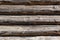 Wooden dark faded brown logs background with cracks and splits