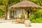 Wooden deck chairs under a palm tree umbrella on a sandy exotic beach with tall palm trees