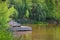 Wooden deck with comfortable rustic chairs jutting out into pond surrounded by lush greenery with coy swimming in water - Lazy