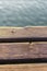 Wooden deck of a jetty in Lake Garda. The sun is reflected in the water. The wood is warm, brown in color. Detail, macro