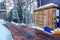 Wooden deck with snow shovel and bucket against storage cabinet and gray wall