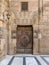 Wooden decorated copper plated door and stone bricks wall at the courtyard of Al-Sultan Barquq mosque, Old Cairo, Egypt