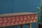 Wooden desk with design in red and pink colors. With drawers. In a room with blue walls. Undecorated workspace.