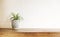 Wooden desk table top with tree pot on white wall, with copy space