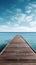 A wooden dock jetty pier with a tropical blue ocean summer sky background.