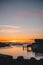 Wooden dock stretching out towards the horizon, surrounded by glistening blue waters at sunset.