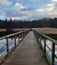 Wooden dock. Wooden path. Walking on the bridge. Lake, bridge, clouds. People walking on the brigde.