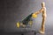 A wooden doll carries a Christmas treel in metal shopping cart. Concept of buying Christmas decorations, moneys, miniature. Stay