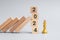 wooden Dominoes falling against 2024 stop blocks with golden Chess King figure. Business, Risk Management, Solution, economic,