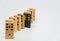 Wooden dominoes sequence with black plastic domino on white background with selective focus