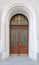 Wooden door with glass and arched window, framed with stucco ornament. historic house entrance