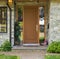 Wooden door of a house with pair of shoes and lilac watering can outside