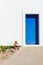 The wooden door is a rich blue color in a white wall. Bright afternoon sunlight