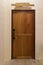 Wooden door with wood nameplate on the top in dark empty room.